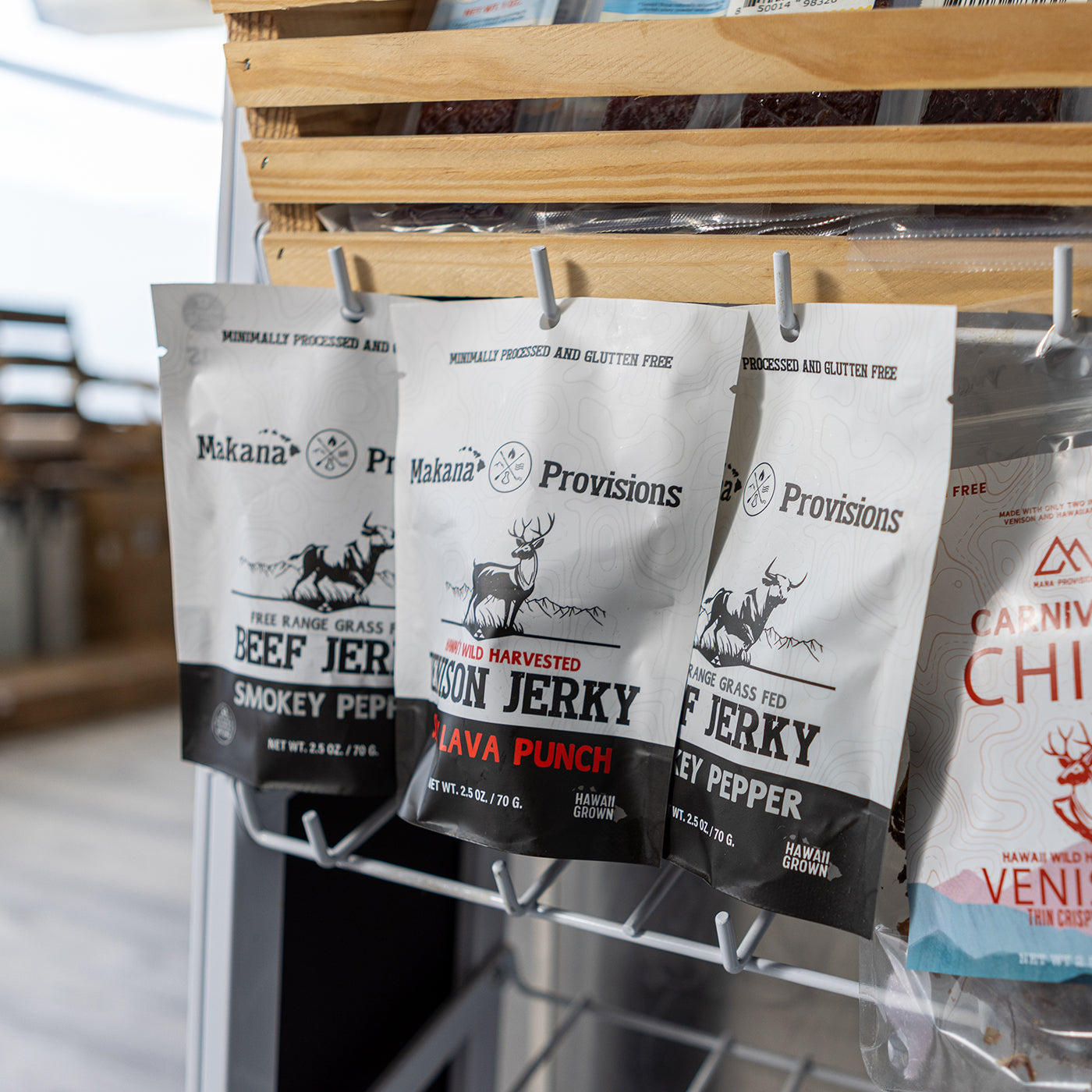 makana wild venison jerky and beef jerky packages hanging on shelf in market